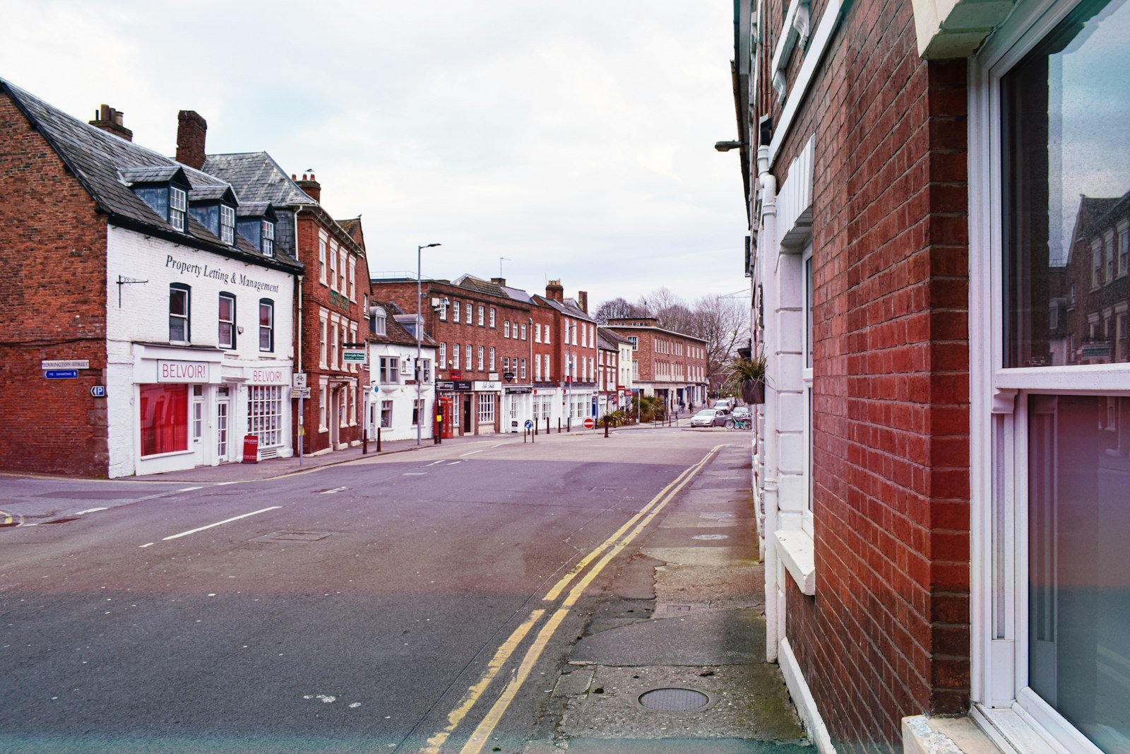 Street view in Calne featuring property management storefronts, brick buildings, and a quiet road, relevant to Chippenham Cleaning's services in the area.