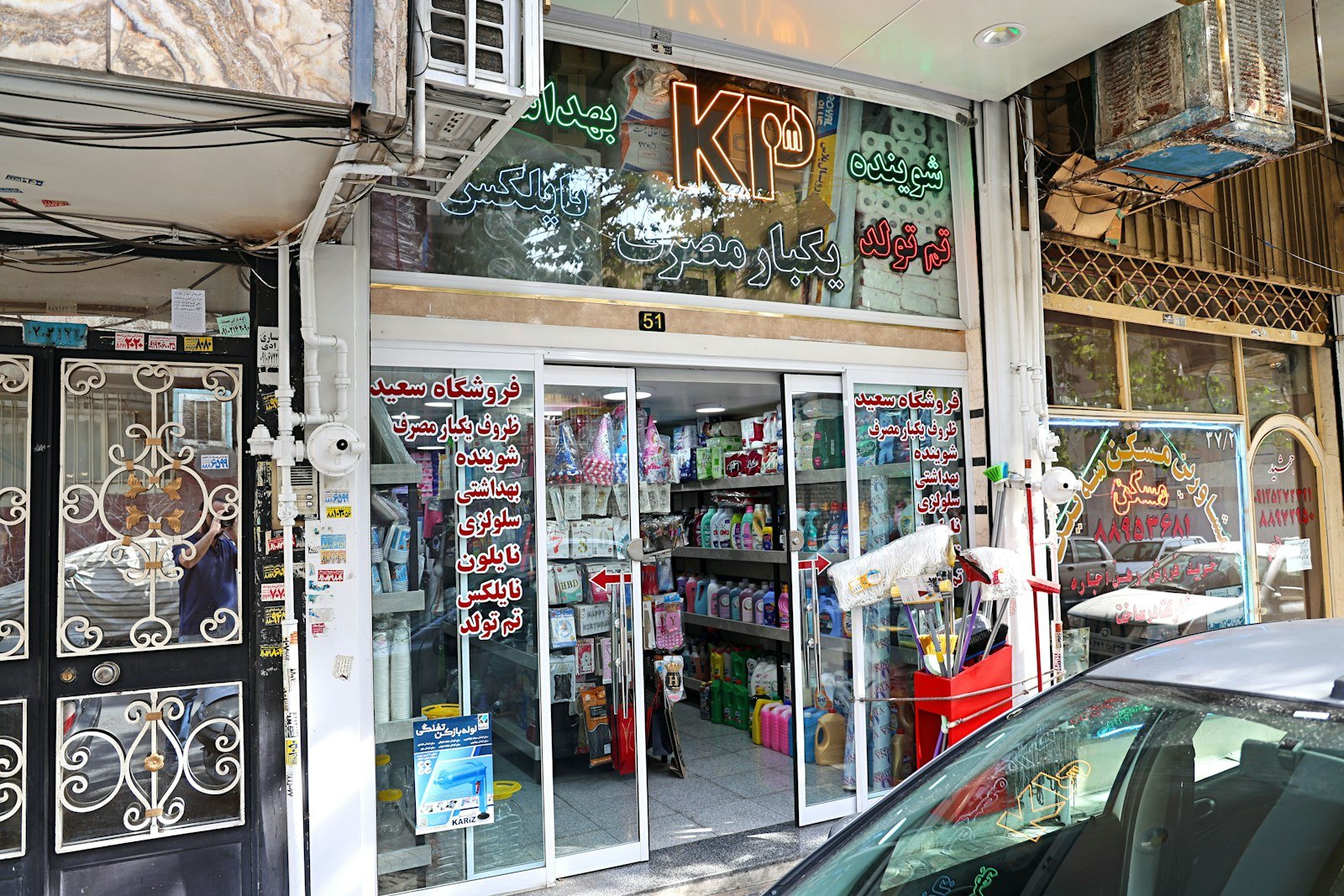 Storefront of a cleaning supplies shop in Calne, featuring various cleaning products, mops, and signage in Arabic, highlighting commercial cleaning services.
