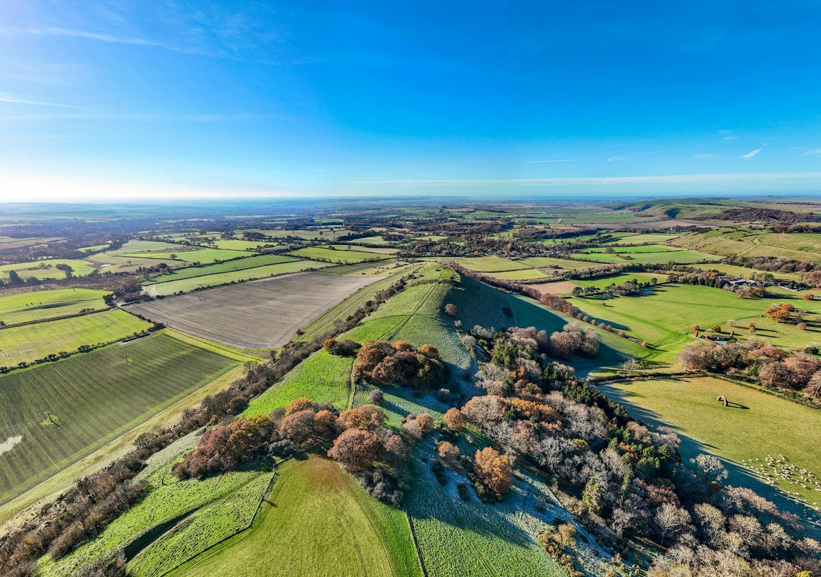 Aerial view of the green countryside in Lyneham with rolling hills, farmland, and scattered trees, representing the local area served by Chippenham Cleaning's services.