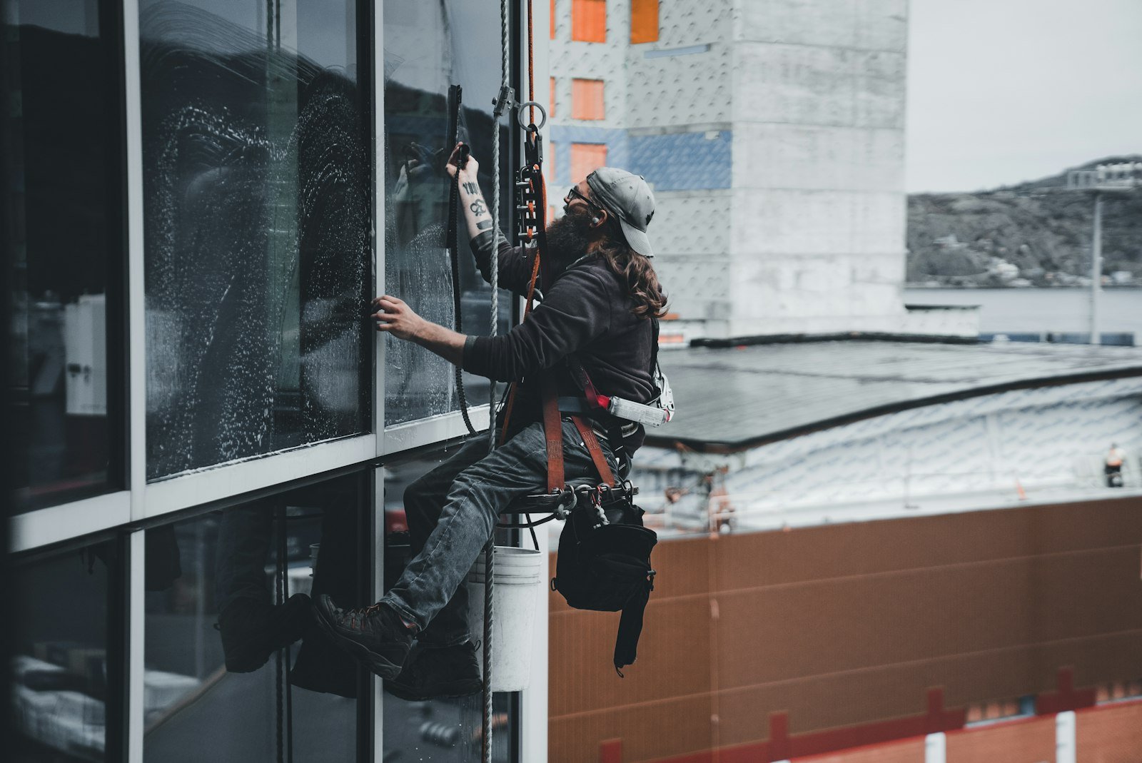Window cleaner using a squeegee on a high-rise building, demonstrating professional cleaning services relevant to office maintenance in Devizes.
